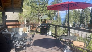 A covered deck with outdoor furniture, a grill, and a red umbrella. - Fun and Relaxing in Tahoe City! (Tahoe City)