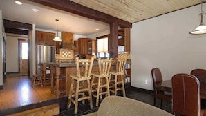Una cocina amplia con taburetes de madera, una isla central y una zona de comedor con mesa y sillas.
