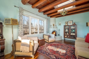 Una sala de estar acogedora con chimenea, vigas de madera y un tapete grande.