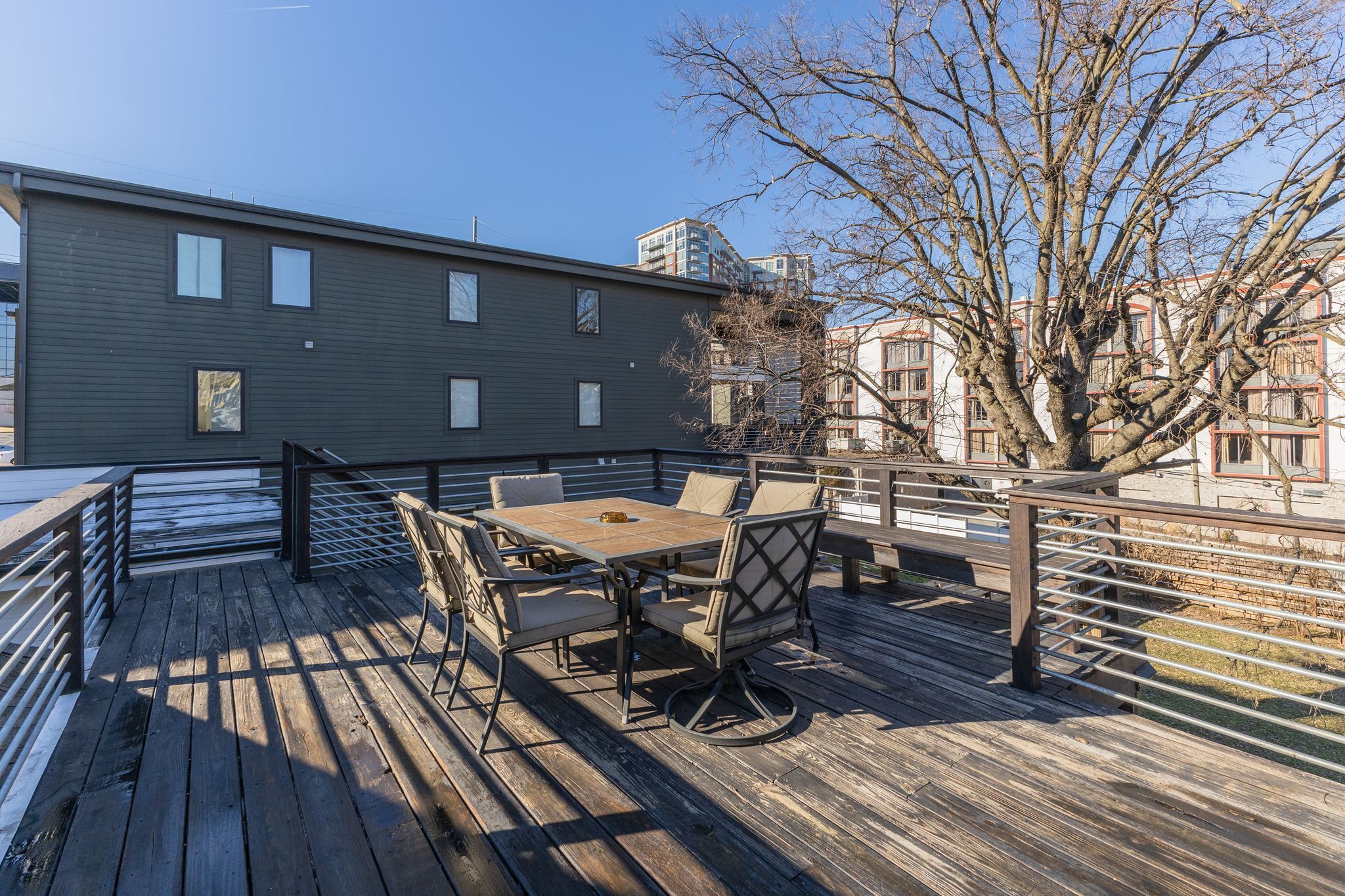 Une terrasse en bois avec une table et des chaises, donnant sur un immeuble doté de nombreuses fenêtres et de balcons.
