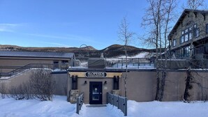 A building entrance with a sign reading "SLOPESIDE CONDOMINIUMS" and a snow-covered path leading to it. - Slopeside Beautifully Renovated Kitchen & Bath 1.5 Baths Deck Outstanding Views (Keystone)