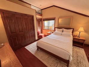 A bedroom with a large bed, a wooden wardrobe, a nightstand with a lamp, and a window with a view. - 100% Remodeled Luxury Slopeside 2760 One Bedroom 2 Baths Full Kitchen Deck Views (Keystone)