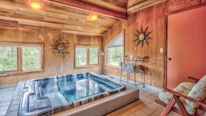 A wooden cabin interior with a hot tub, large windows, and a rustic decor. - AC, Luxurious, vaulted ceilings, great home for couples, dogs allowed (Sunriver)