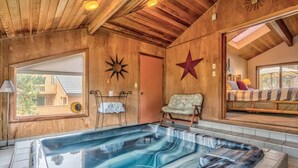 A wooden interior with a hot tub, a chair, and a bed with a view. - AC, Luxurious, vaulted ceilings, great home for couples, dogs allowed (Sunriver)