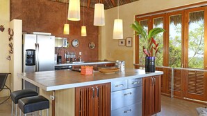 Una cocina con una isla grande, armarios de madera y lámparas colgantes.