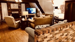 Een gezellige woonkamer met een met baksteen beklede open haard, een televisie en comfortabele zitplaatsen.