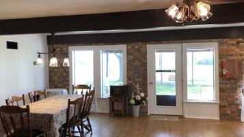 A dining area with a wooden table and chairs, a ceiling fan, and a brick wall.