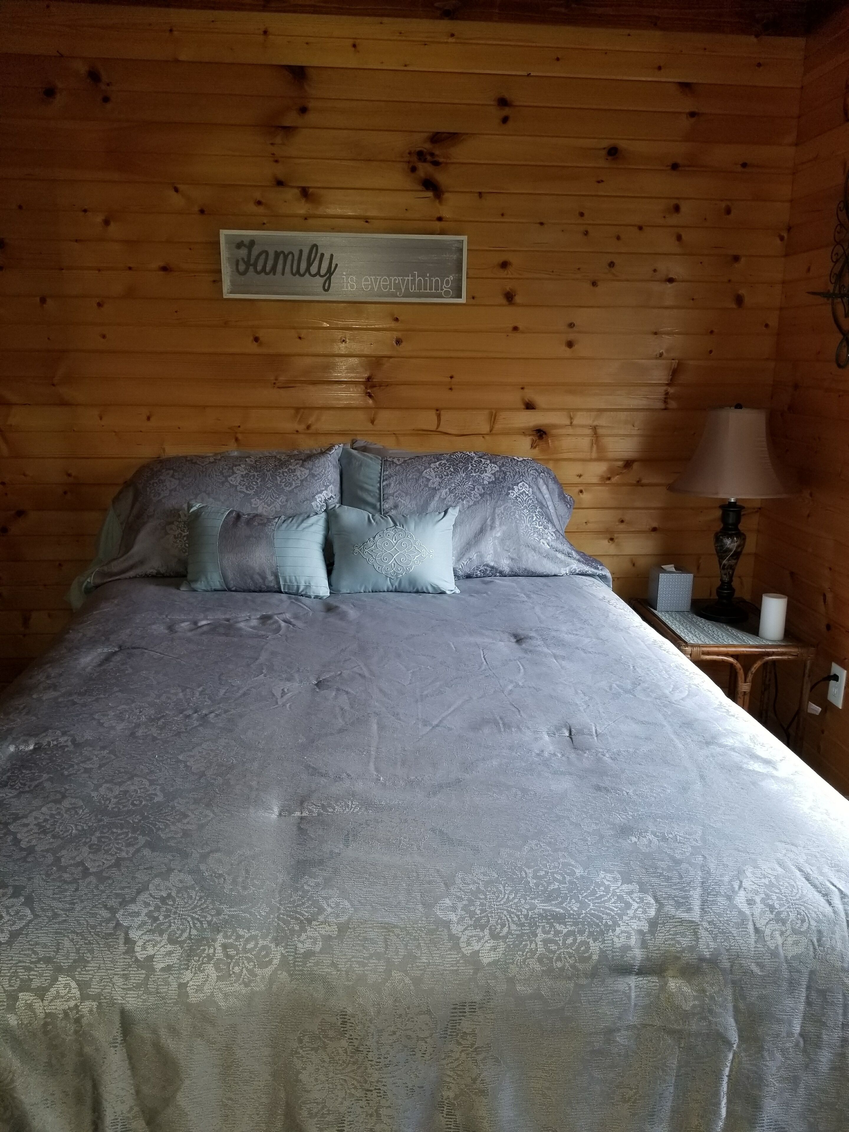 Une pièce aux murs lambrissés, avec un lit, des oreillers, une table de chevet, une lampe et une pancarte sur laquelle on peut lire : « La famille, c’est ce qui compte le plus. »