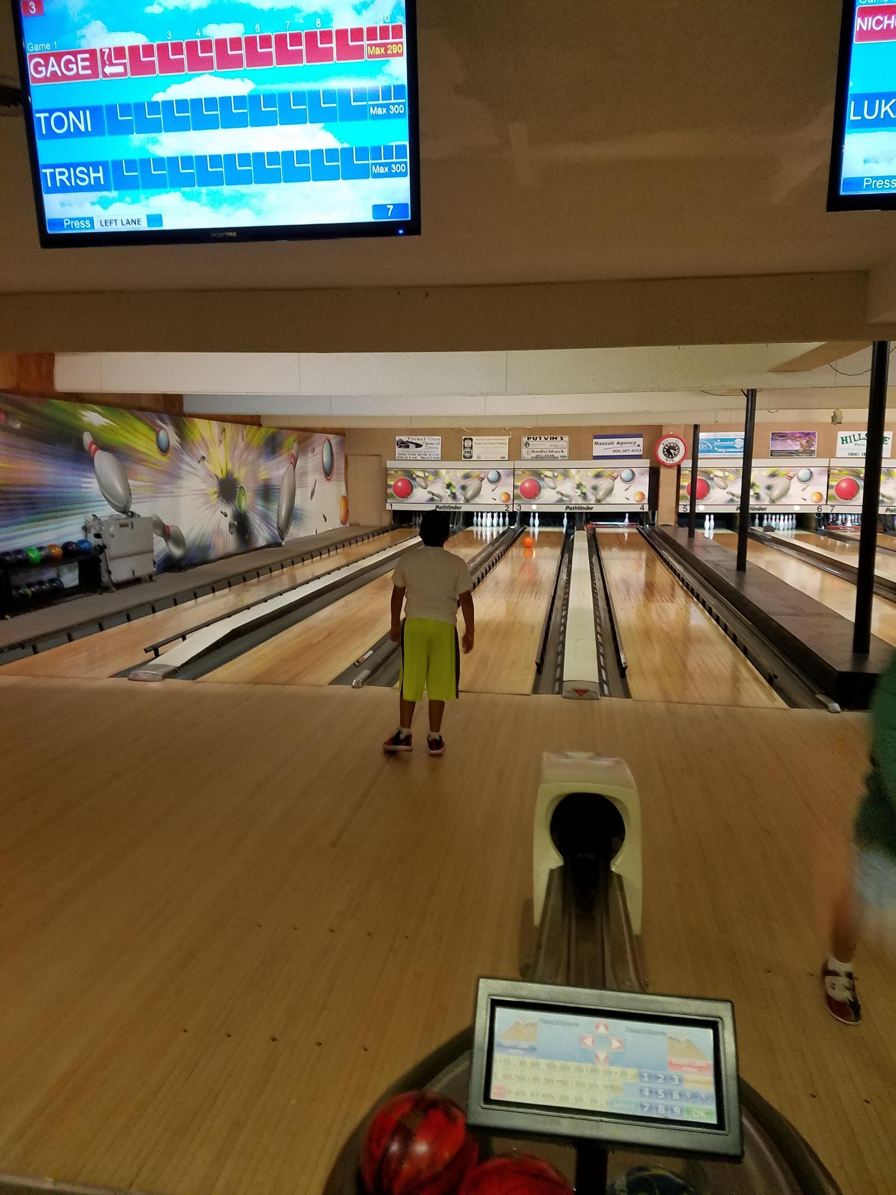 A bowling alley with multiple lanes and a digital scoreboard.