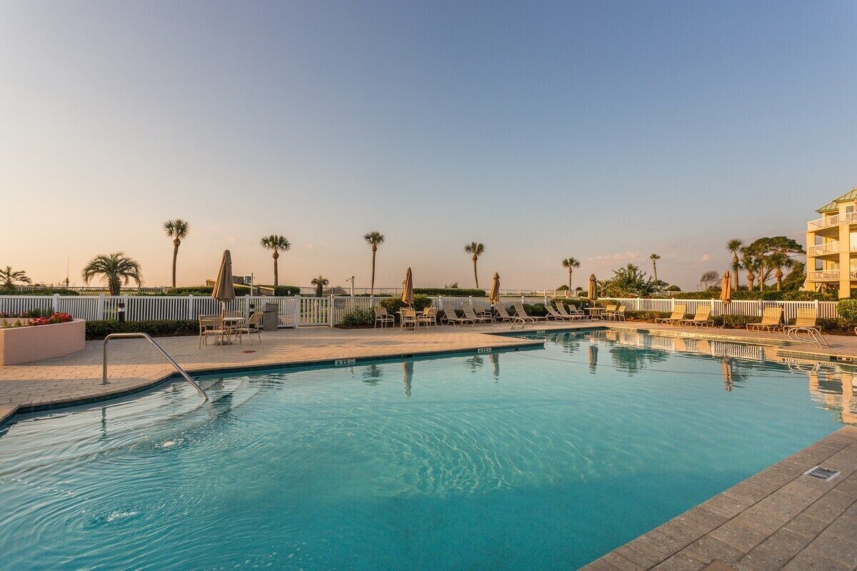 Piscina com espreguiçadeiras e palmeiras.