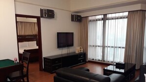 A hotel room with a bed, a TV, a sofa, a pool table, and large windows with curtains. - Residency Suites At Times Square (Kuala Lumpur)