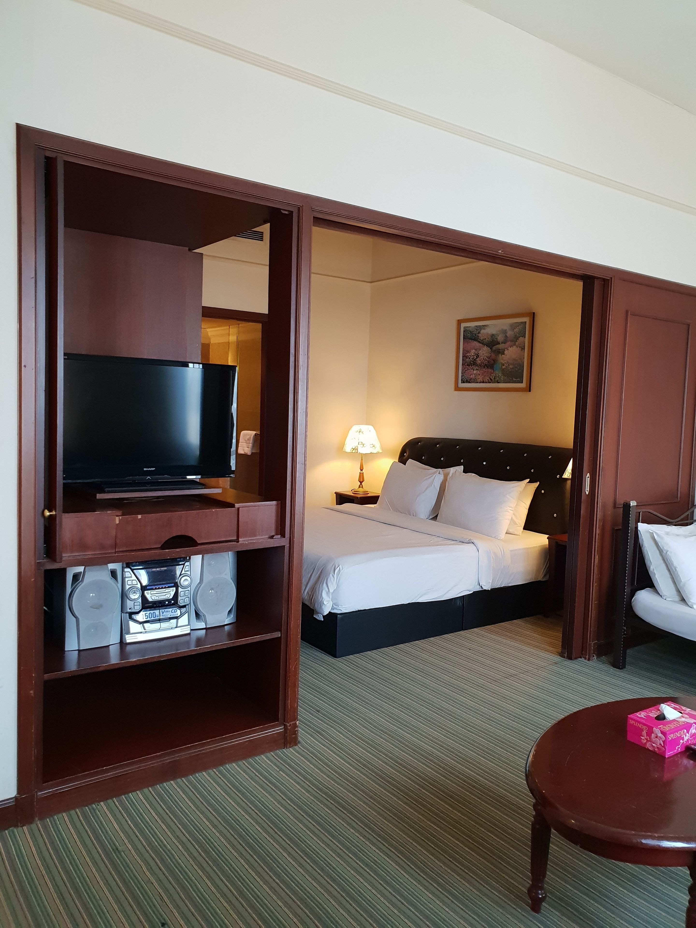 A hotel room with a bed, a TV, a desk, and a chair.