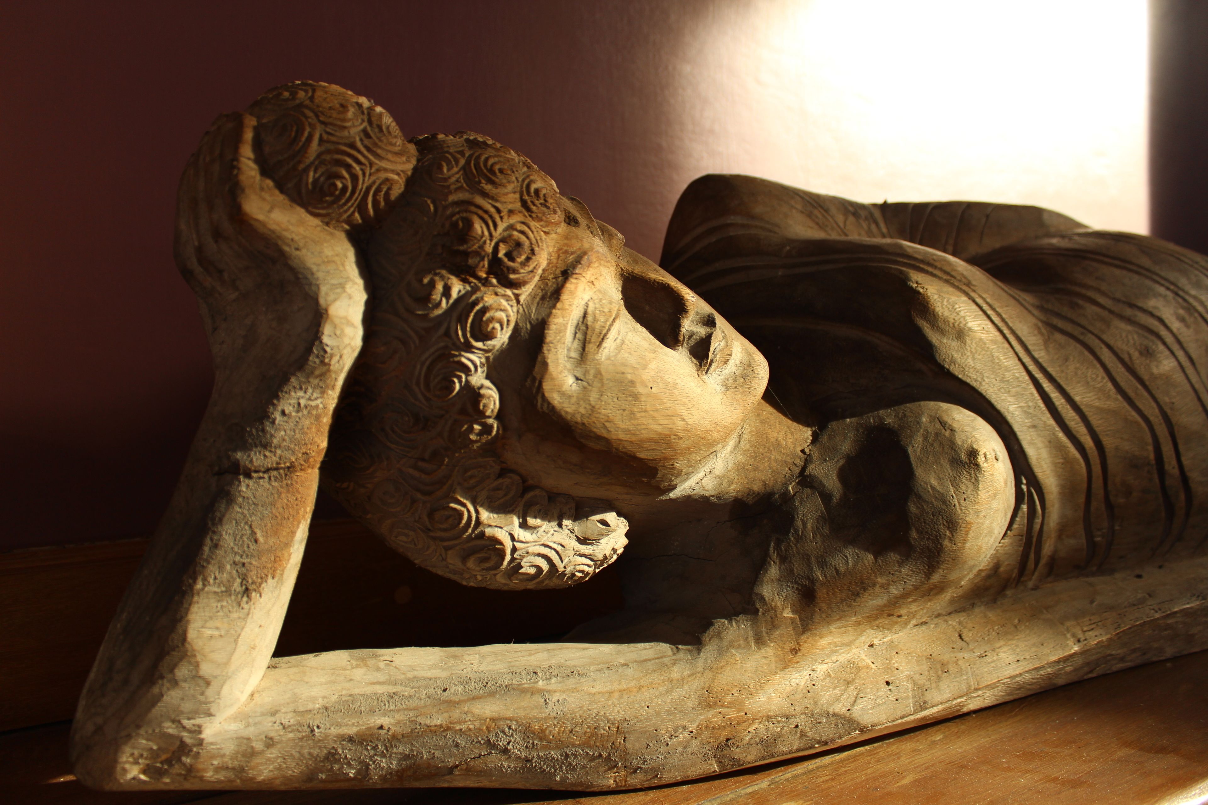 Una escultura de una figura reclinada con tallas intrincadas.