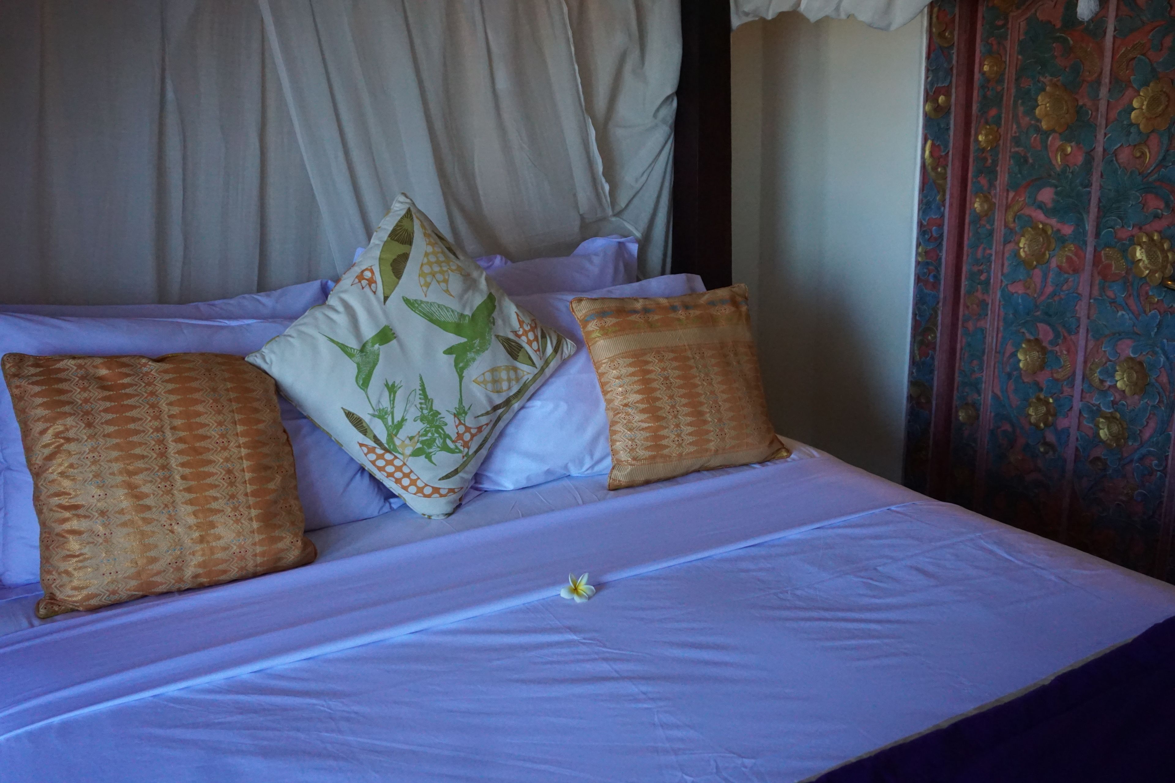 Cama com roupa de cama branca e almofadas estampadas.