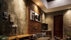 A modern living room with a brick accent wall, a wooden coffee table, a sofa, and a TV.