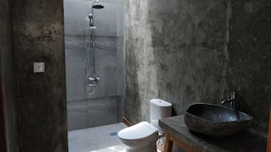 A bathroom with a shower, toilet, and a large basin sink.