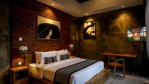 A modern bedroom with a brick wall, a large bed, a desk, and two wall-mounted lamps.