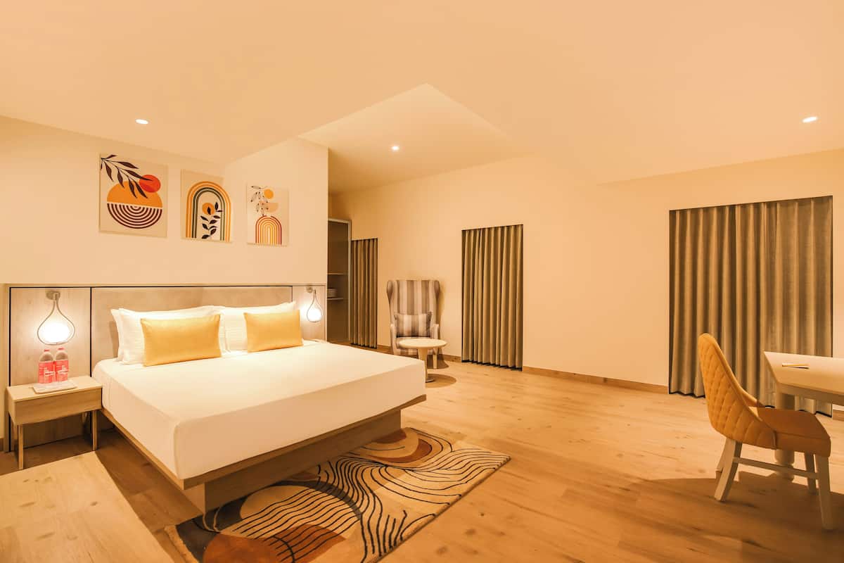 A modern hotel room with a large bed, bedside tables, a desk, and a chair.