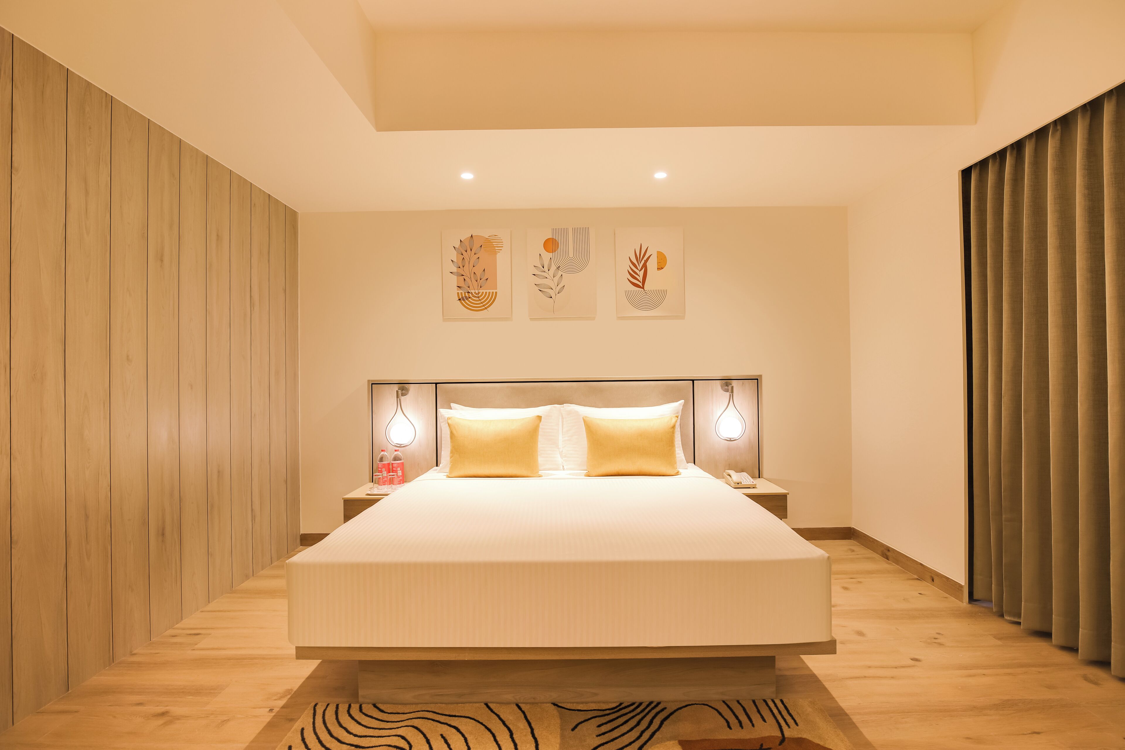 Une chambre moderne avec un grand lit, des murs recouverts de panneaux en bois et trois œuvres d’art accrochées au mur.