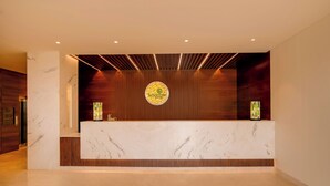 Un área de recepción con mostrador de mármol, paneles de madera y un emblema circular en la pared.