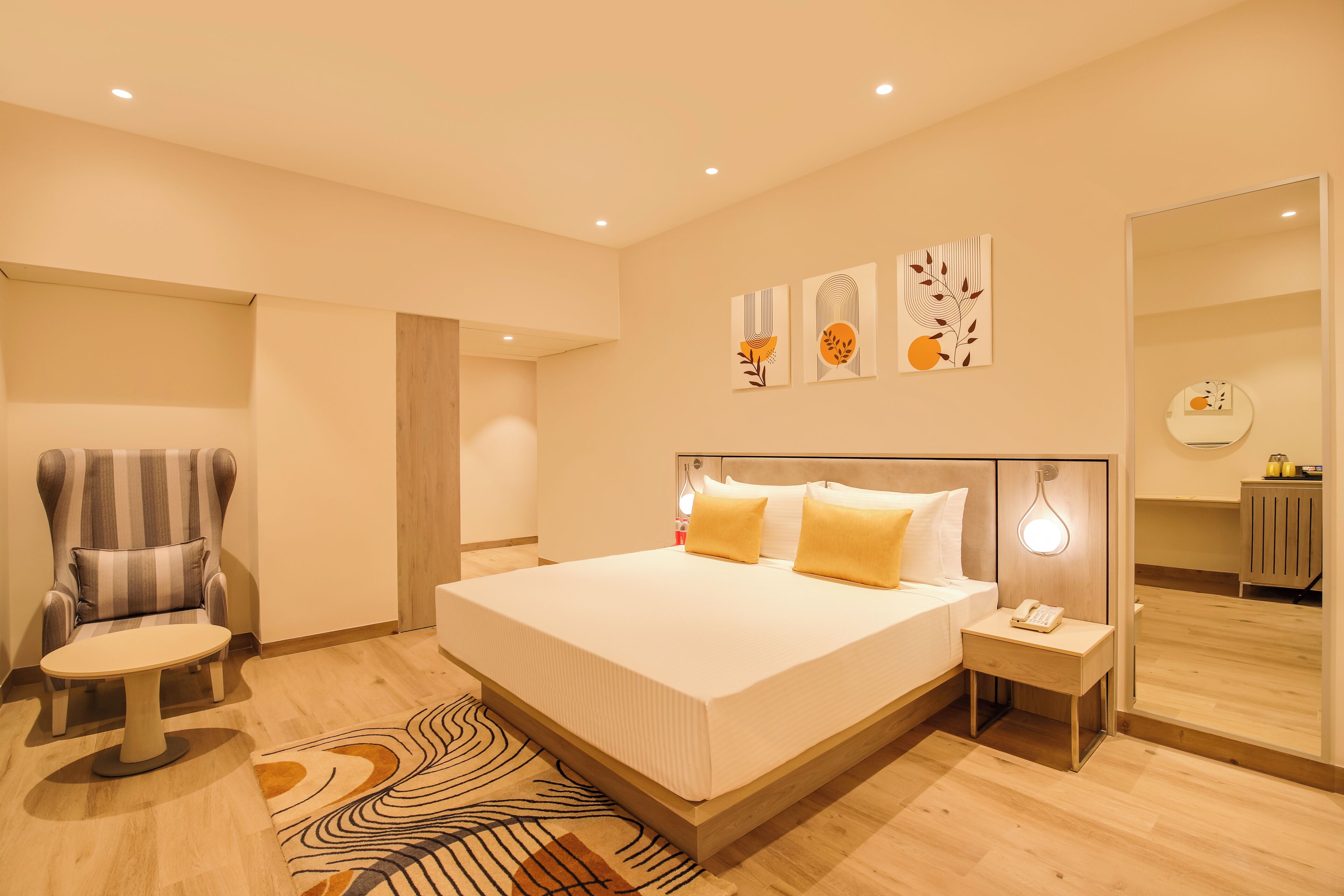 A modern bedroom with a large bed, a chair, a bedside table, and artwork on the wall.