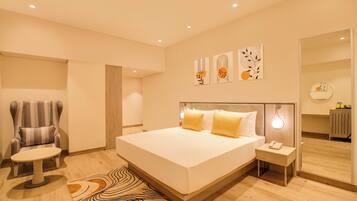 A modern bedroom with a large bed, a chair, a bedside table, and artwork on the wall.