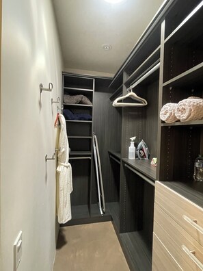 A walk-in closet with hanging space, shelves, and a mirrored section.