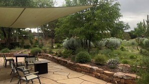 Une terrasse avec un sol en pierre, des meubles d’extérieur et une variété de plantes.