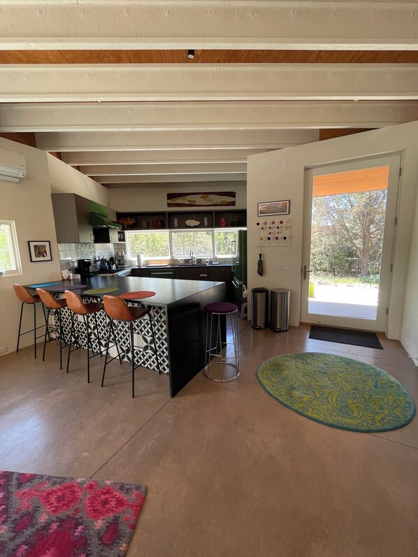 A modern kitchen with a central island, bar stools, and a large window.