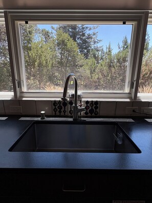 Una cocina con ventana sobre el fregadero, un grifo y una etiqueta de extintor.