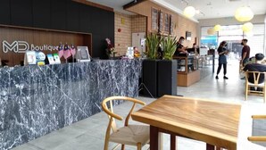 Un elegante hall de hotel boutique con recepción de mármol, mobiliario de madera y un interior limpio y bien iluminado.
