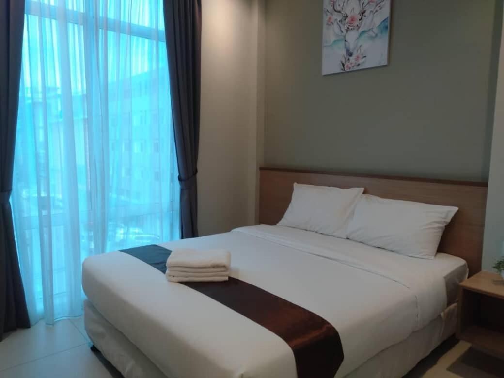 A neatly made bed with white linens and a brown accent, a wooden headboard, and a painting on the wall.