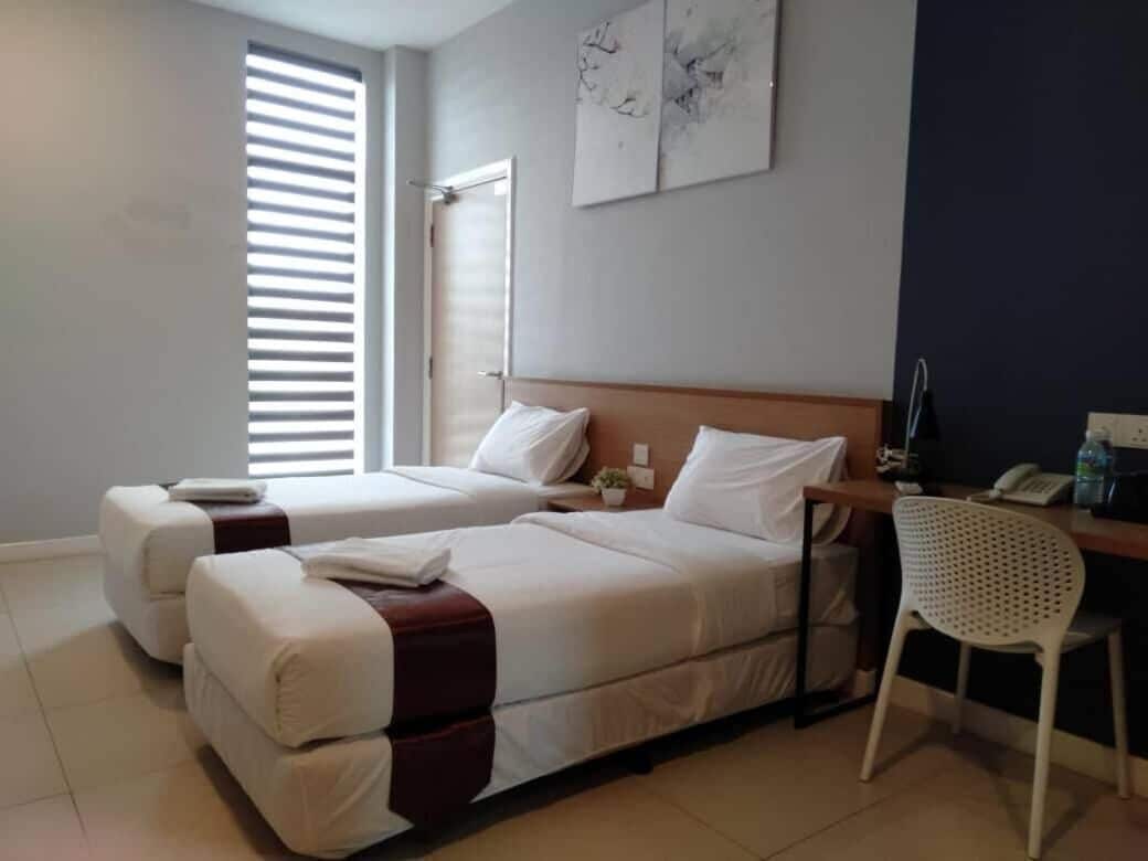 Une chambre d’hôtel avec deux lits, un bureau et une chaise.
