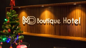 Letrero del Boutique Hotel con fondo de madera y un árbol de Navidad con luces.