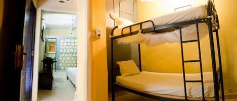 Una cama litera con escalera, una cama individual al fondo y una puerta que da a otra habitación.