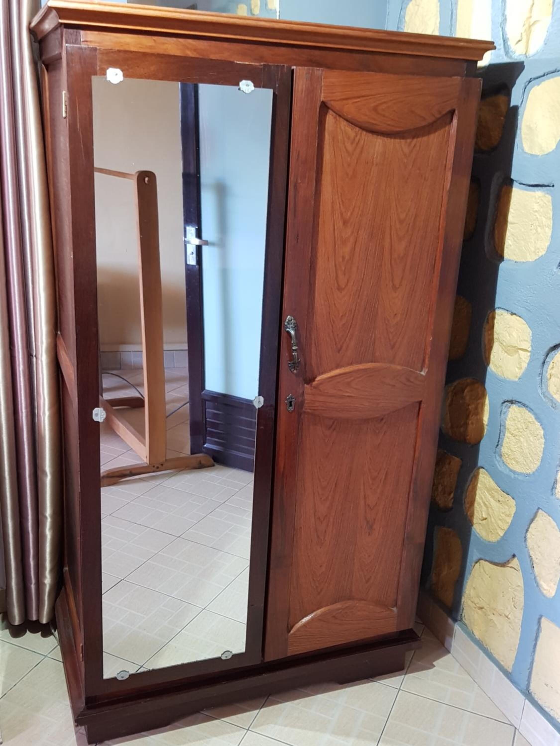 A wooden wardrobe with a mirrored door and a handle.