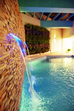 Una piscina con un muro de ladrillo y una cascada.