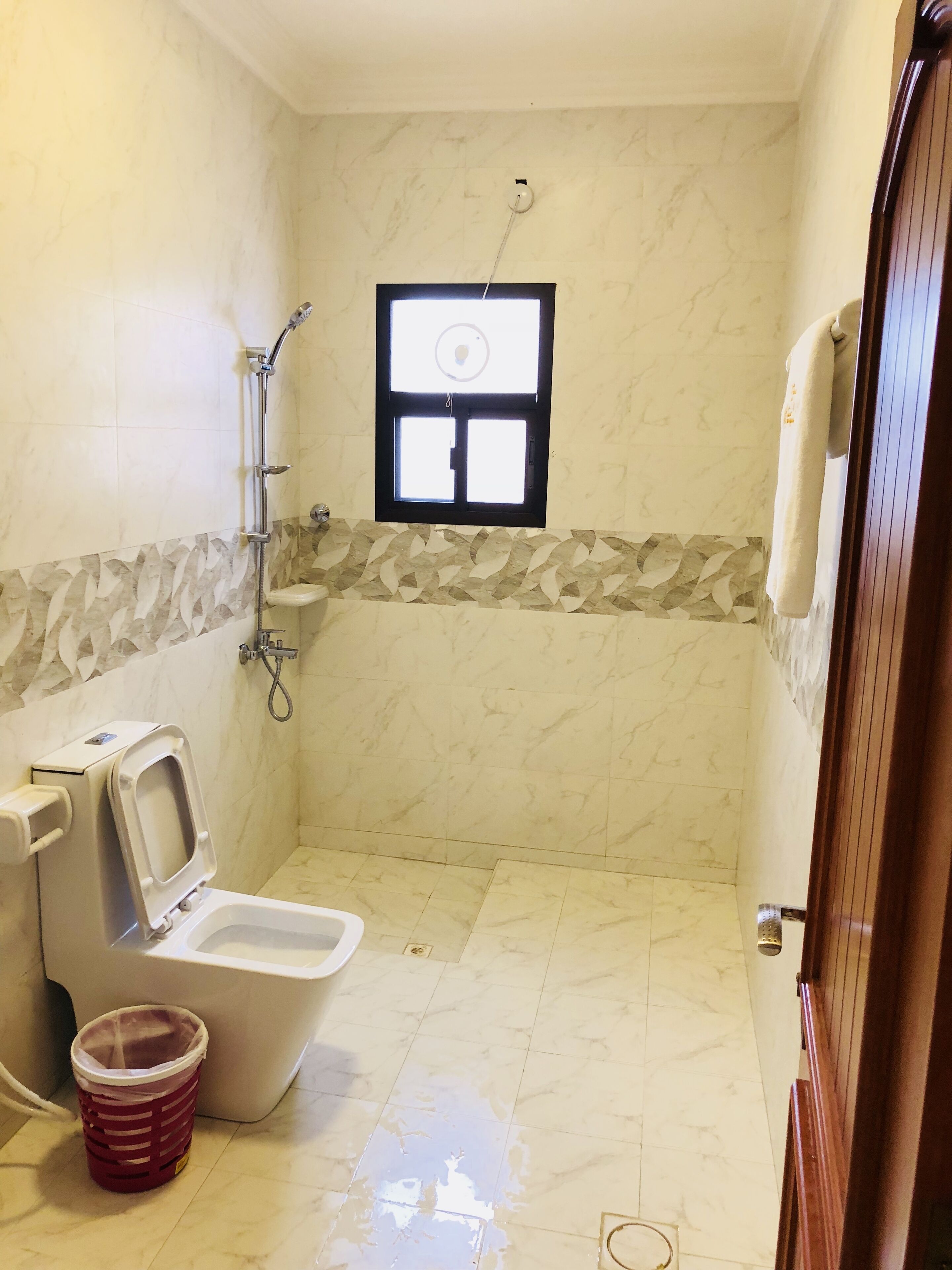 Une petite salle de bain avec des toilettes, une douche et une fenêtre.