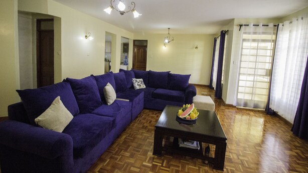 Uma sala de estar com sofá seccional, mesa de centro de madeira com frutas e um candelabro.