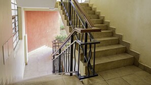 Uma escada com corrimão e um patamar com uma porta que dá para outro cômodo.