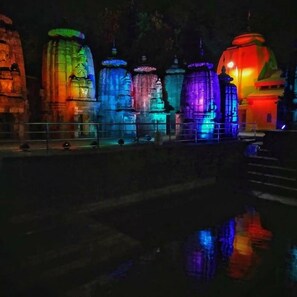 A series of illuminated structures with a reflective water surface in the foreground. - Nest Guest House (Bhubaneshwar)