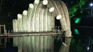 A nighttime view of a unique, curved structure with a series of circular openings, reflecting on the water below. - Nest Guest House (Bhubaneshwar)