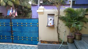 A blue gate with yellow flowers, a small shrine, and potted plants. - Nest Guest House (Bhubaneshwar)