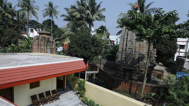 A building with a red roof and a small porch area with four wooden chairs. - Nest Guest House (Bhubaneshwar)