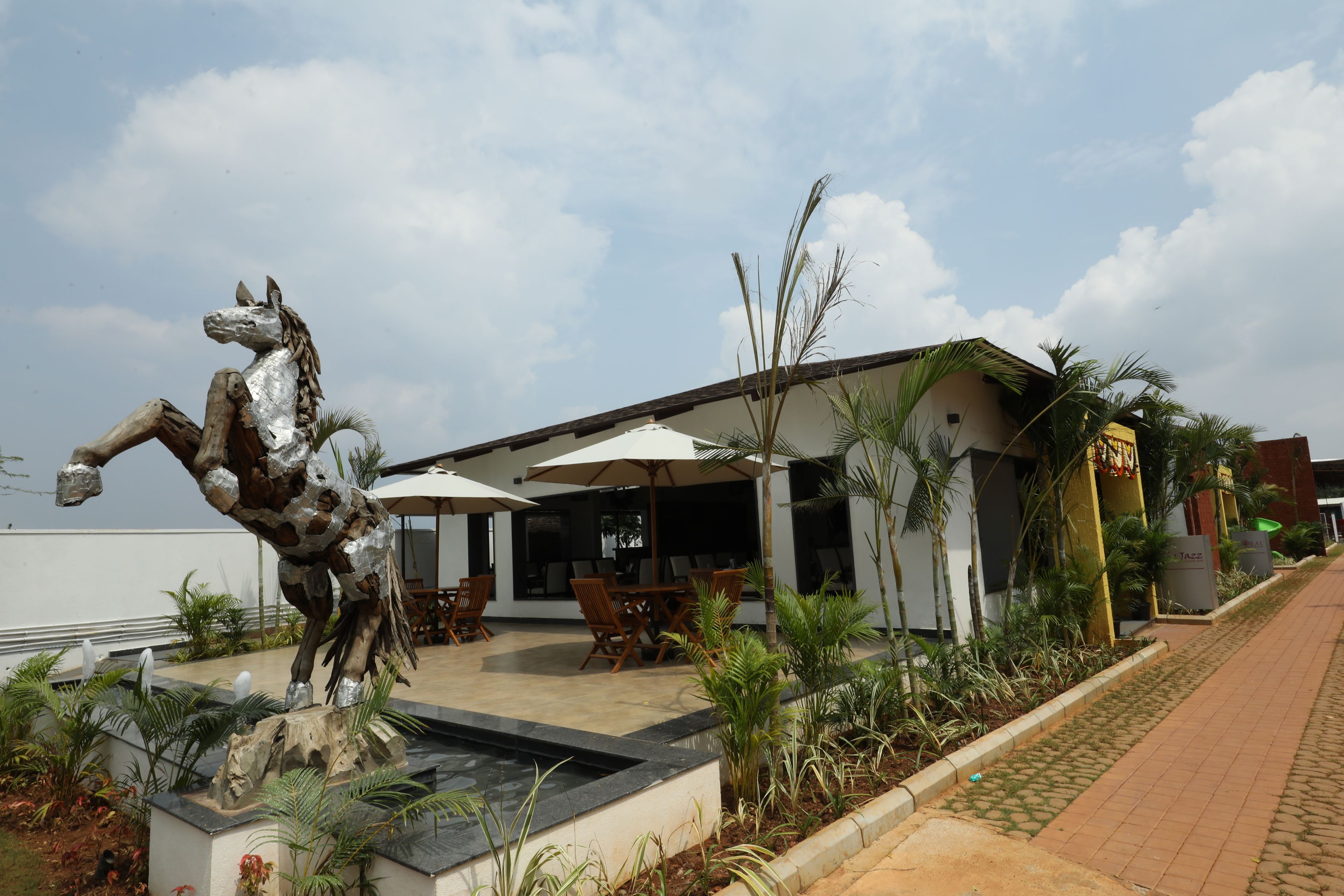 A building with outdoor seating, a horse statue, and a paved walkway.