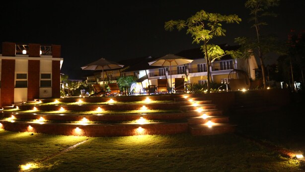 A nighttime view of a hotel with outdoor seating and a well-lit garden area. - The Ocean Pearl Resort And Spa (Dharwad)