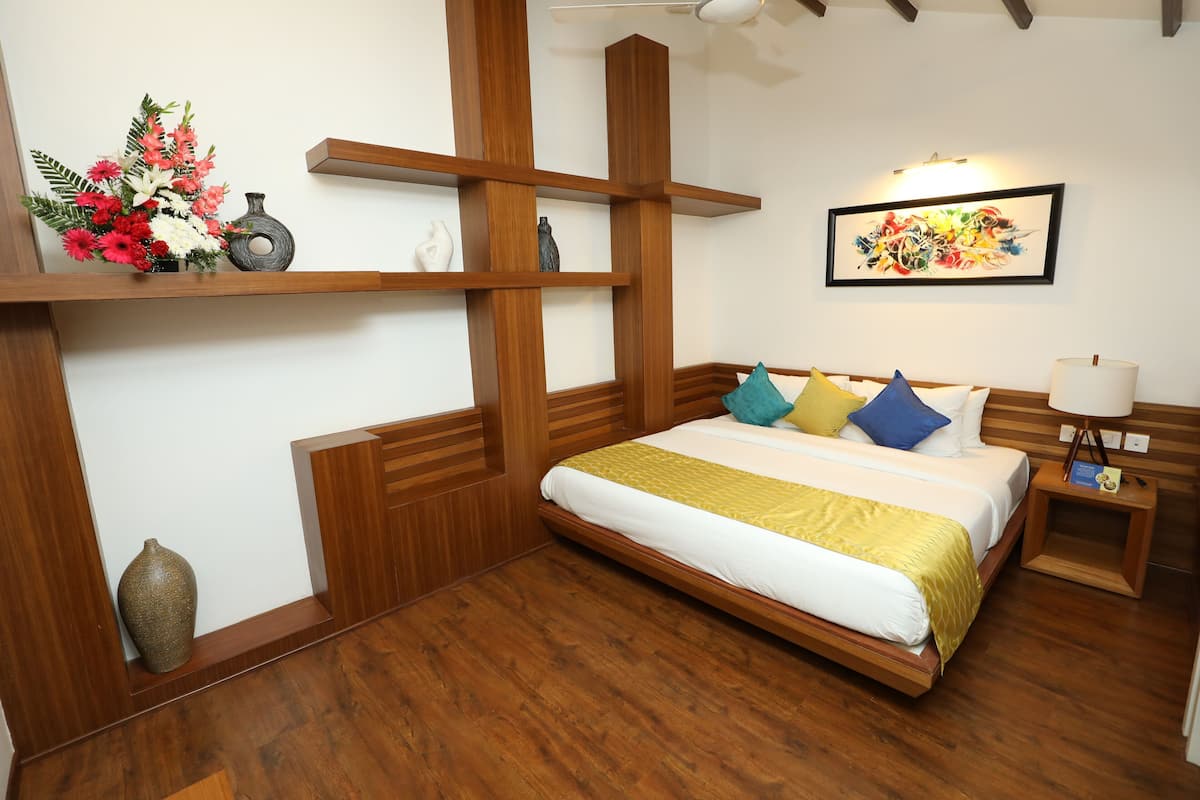 A bedroom with a wooden bed, a nightstand, a wall-mounted shelf with decorative items, and a ceiling fan.