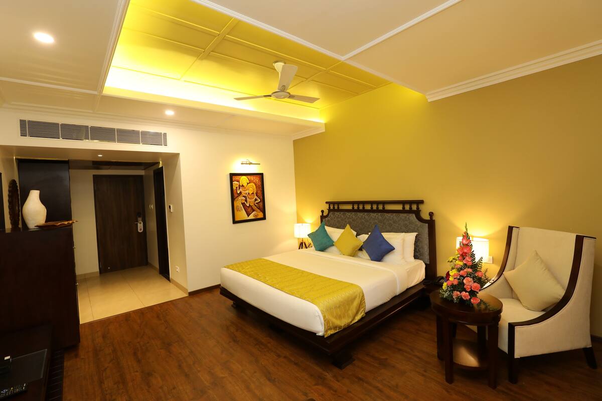 A hotel room with a bed, a chair, a desk, and a ceiling fan.