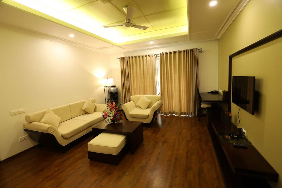 A living room with a sofa, ottoman, coffee table, lamp, and curtains.