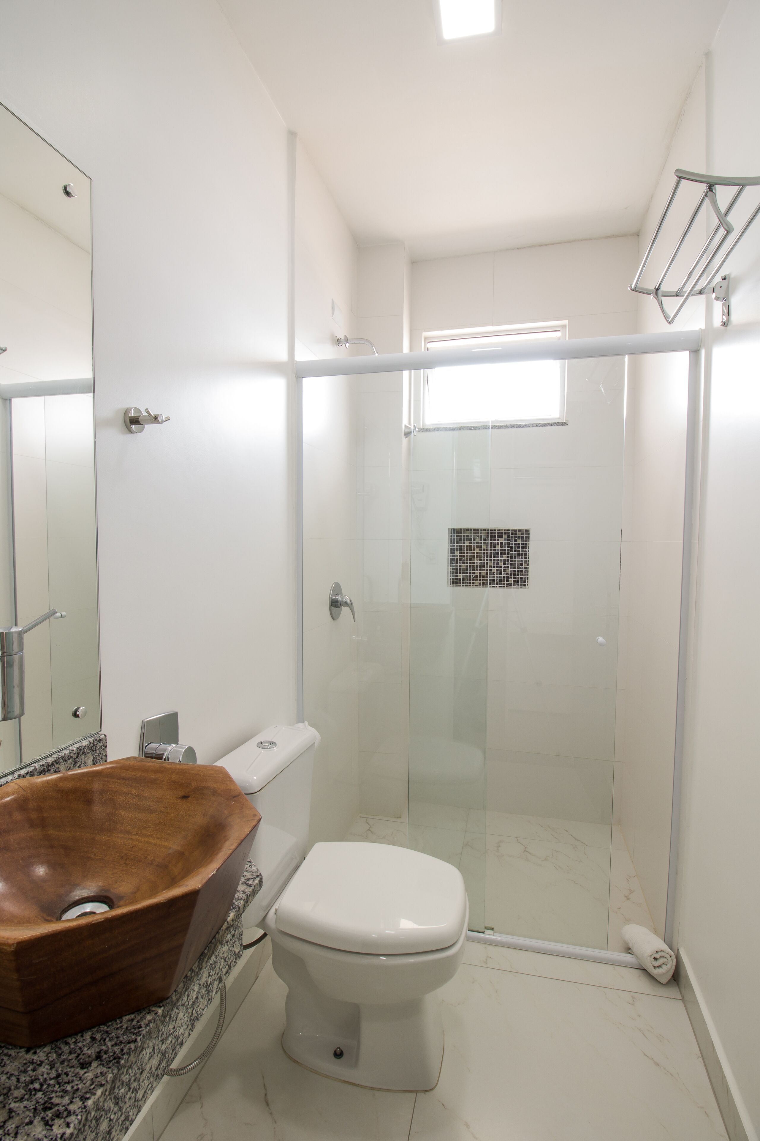 A modern bathroom with a wooden sink, white toilet, and a glass-enclosed shower.